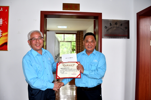 公司工會主席許鋒（右）向公司監(jiān)事會主席、捐書人胡夏生頒發(fā)《收藏證書》